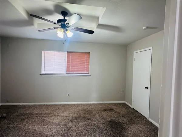 an empty room with a chandelier fan and windows