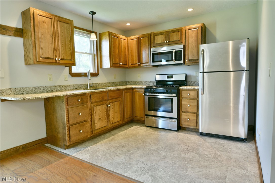 754 Warner Road Hubbard, OH 44425 - Photo 15 of 46 Kitchen featuring wood cabinetry, light-toned countertops, and stainless steel appliances including a refrigerator, range, and microwave