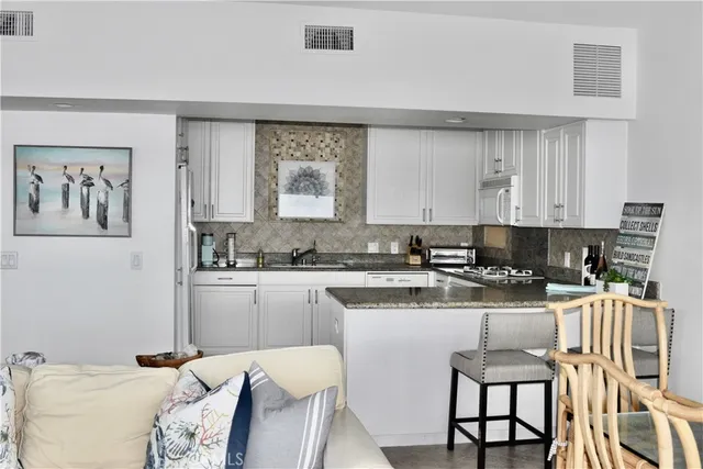 a kitchen with a stove a sink and white cabinets