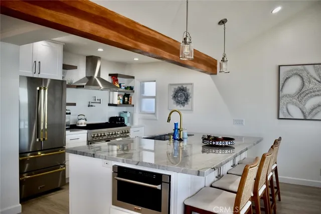 a kitchen with stainless steel appliances granite countertop a refrigerator a stove a sink dishwasher and white cabinets with wooden floor