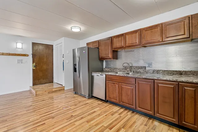 a kitchen with stainless steel appliances granite countertop a refrigerator and wooden cabinets