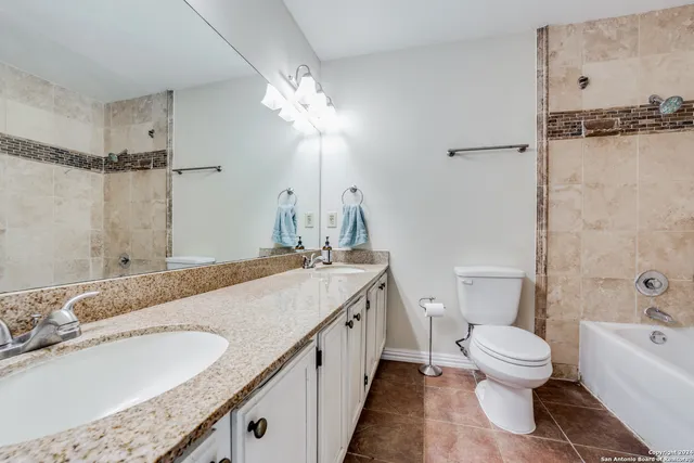 a bathroom with a granite countertop sink a toilet and a bathtub