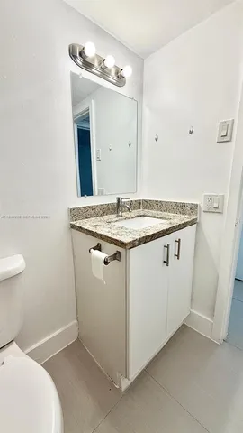 a utility room with a sink a toilet and mirror