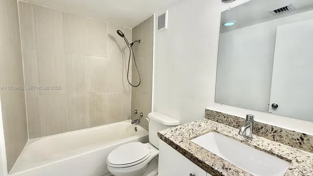 a bathroom with a granite countertop sink toilet mirror and shower