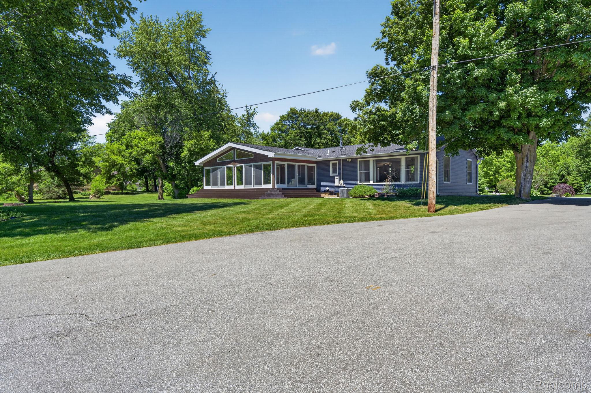 9353 Hill Road Swartz Creek, MI 48473 - Photo 86 of 98 Ranch-style exterior with gray siding, featuring a sunroom with expansive windows and a dark trim