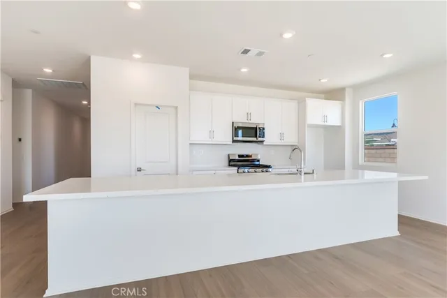 a large white kitchen with kitchen island a sink a stove and white cabinets