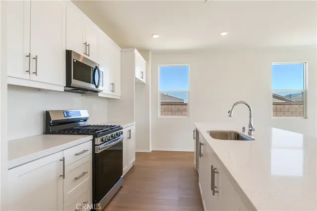 a kitchen with stainless steel appliances granite countertop a sink and a stove top oven with white countertops