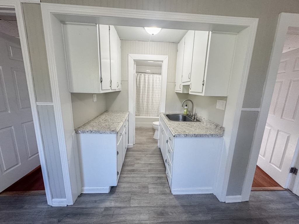 3-5 Noel Street Springfield, MA 01108 - Photo 16 of 28 a kitchen with granite countertop white cabinets and wooden floor