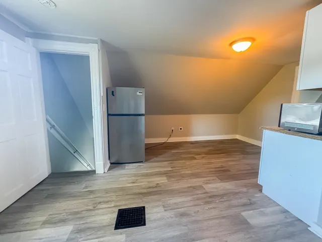 a view of a refrigerator in kitchen and an empty room
