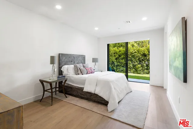 a bed sitting in a spacious bedroom next to a window