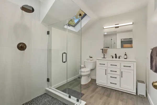 a bathroom with a sink a toilet a mirror and shower