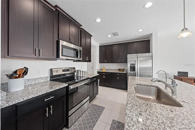 a kitchen with granite countertop a sink a counter space appliances and cabinets