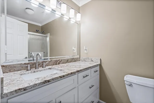 a bathroom with a granite countertop sink a toilet and a mirror