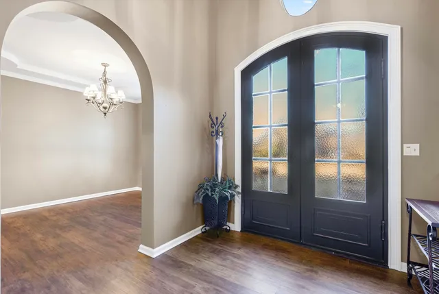 an empty room with wooden floor mirror and windows