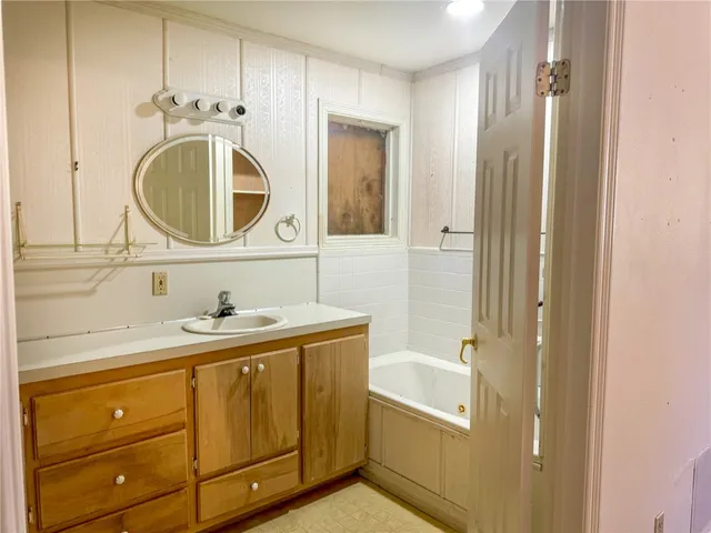 a bathroom with a sink a mirror a vanity and a bathtub
