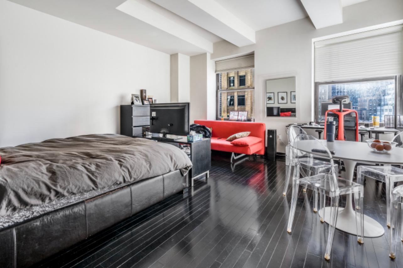20 Pine Street, Unit 2205 Manhattan, NY 10005 - Photo 1 of 10 a bedroom with a bed and wooden floor