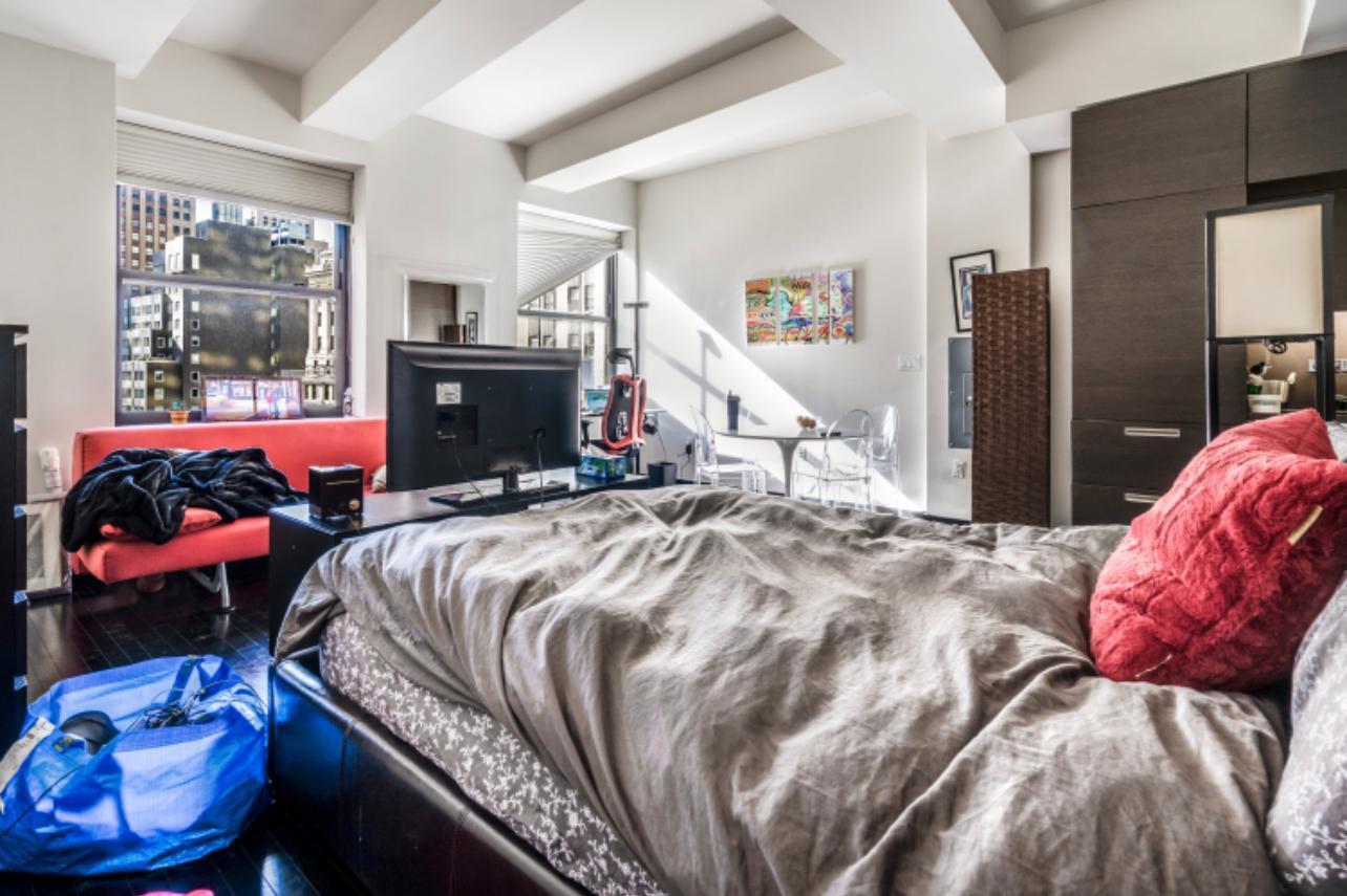 20 Pine Street, Unit 2205 Manhattan, NY 10005 - Photo 5 of 10 a bed sitting in a bedroom next to a window with tv