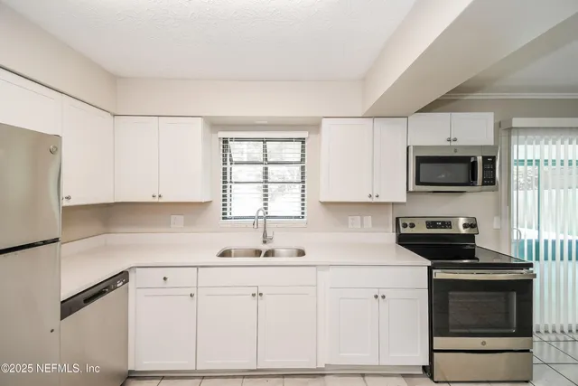 a kitchen with white cabinets stainless steel appliances and sink