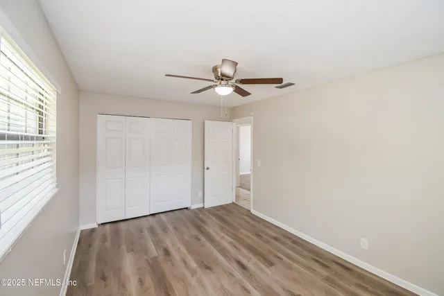 an empty room with a window and a ceiling fan