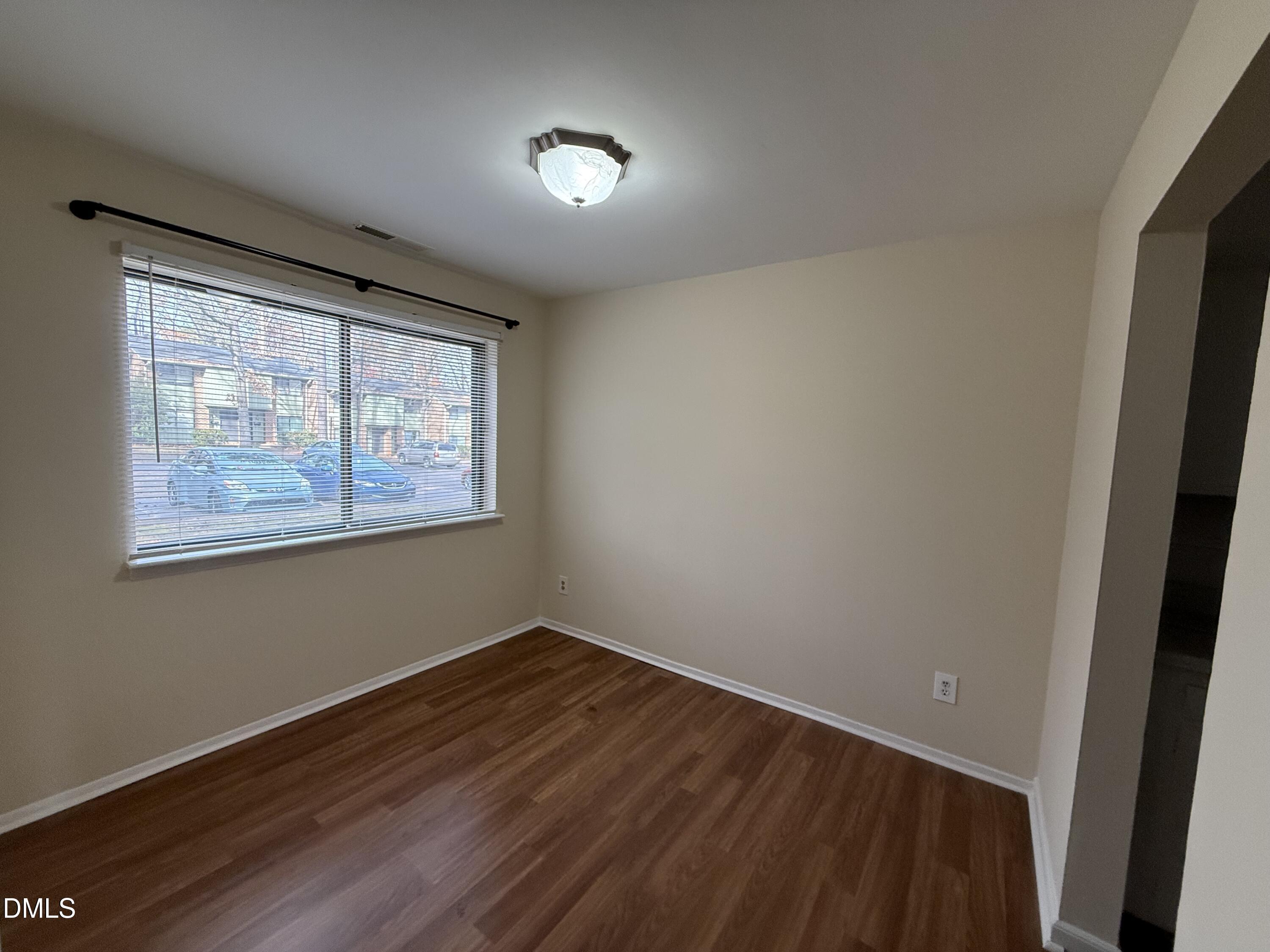 1228 Teakwood Place Raleigh, NC 27606 - Photo 12 of 30 a view of an empty room with wooden floor and a window