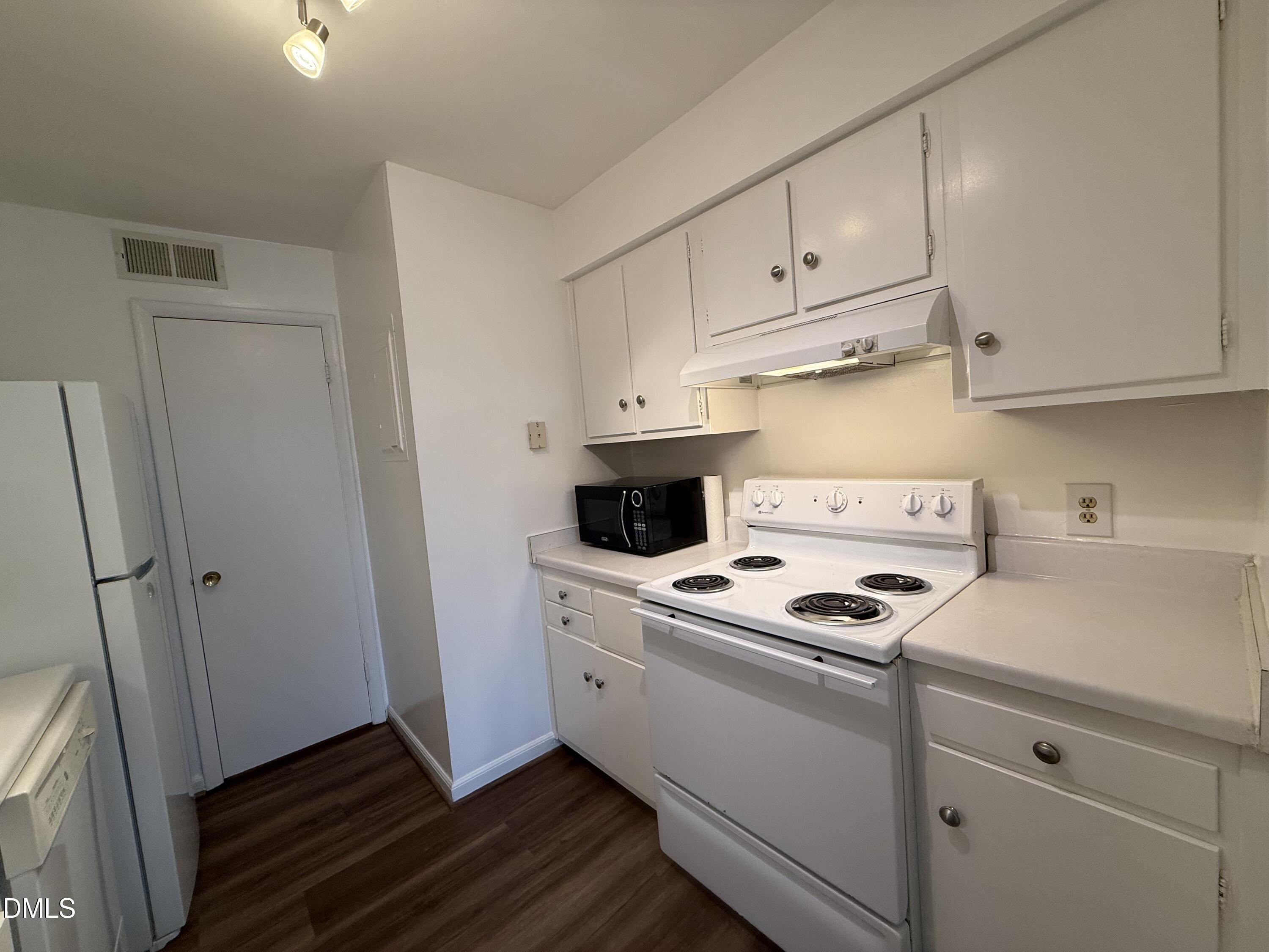 1228 Teakwood Place Raleigh, NC 27606 - Photo 7 of 30 a kitchen with white cabinets and white appliances