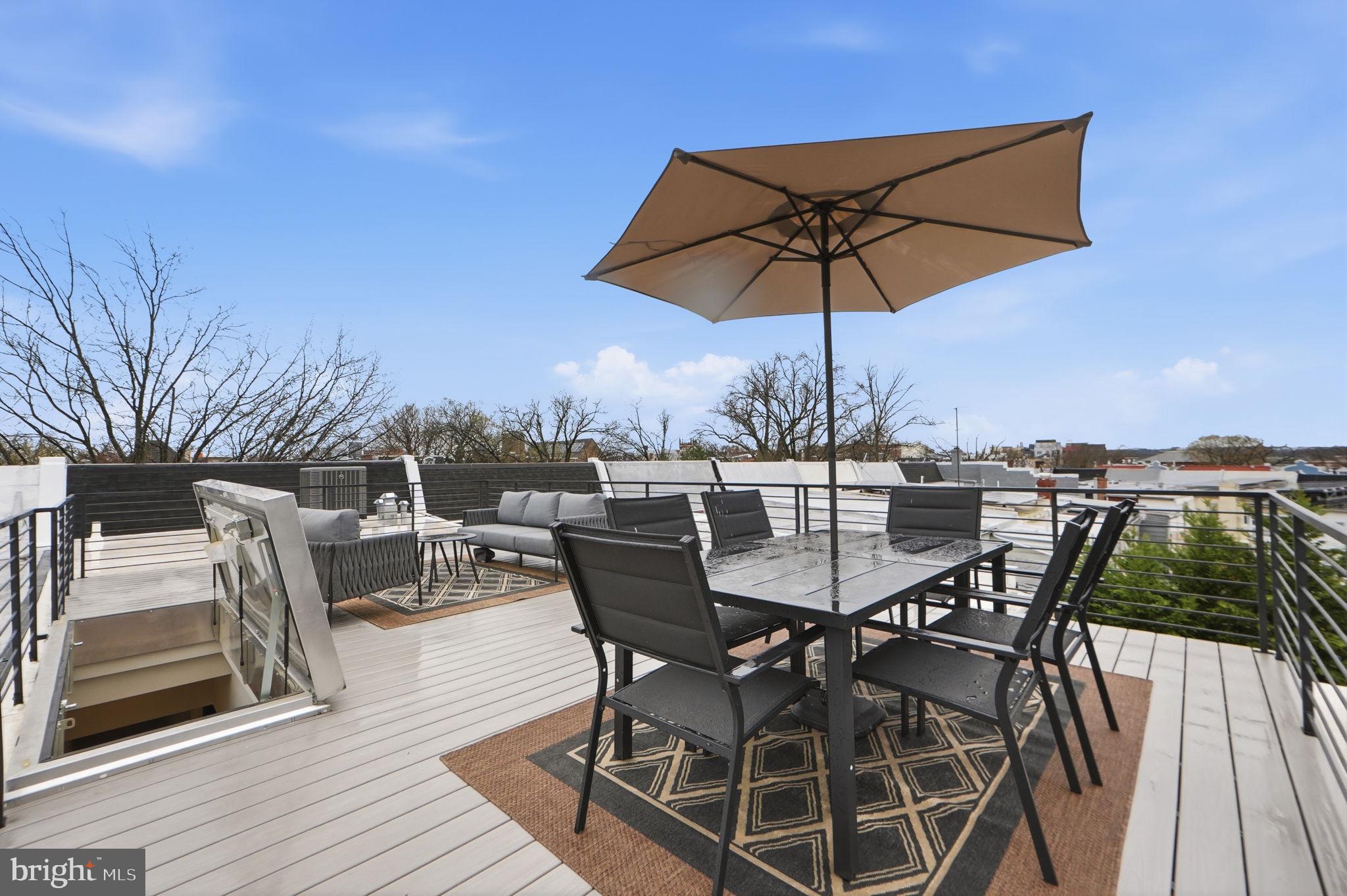 533 Shepherd Street Northwest Washington, DC 20011 - Photo 62 of 69 a view of a roof deck with table and chairs under an umbrella with wooden floor