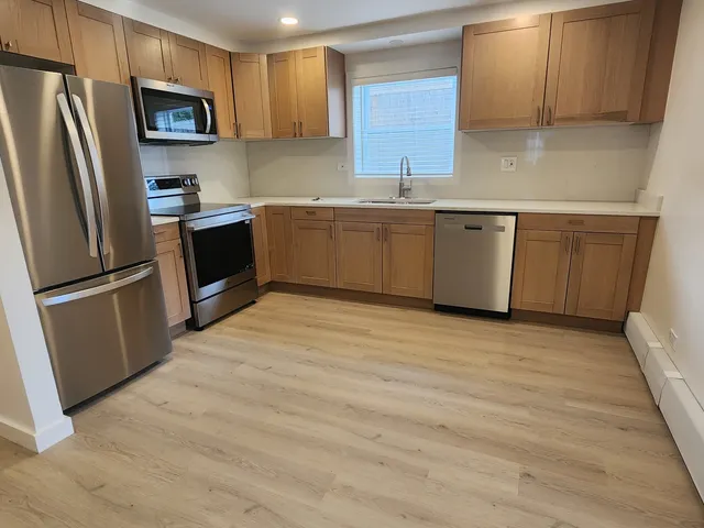 a kitchen with stainless steel appliances granite countertop a refrigerator a sink a stove a microwave and wooden cabinets