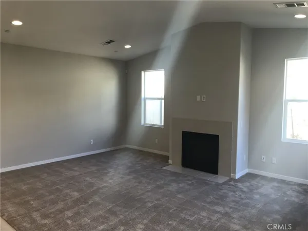 an empty room with a fireplace and windows