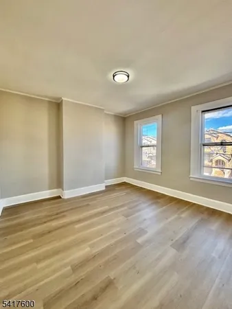 a view of an empty room with window and wooden floor