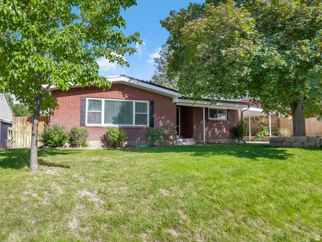 523 South Main Street Payson, UT 84651 - Photo 3 of 41 Brick exterior residence featuring a front lawn, mature trees, a covered entryway, and a covered carport