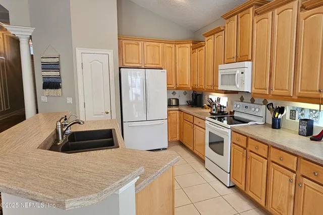 a kitchen with granite countertop a refrigerator sink and cabinets