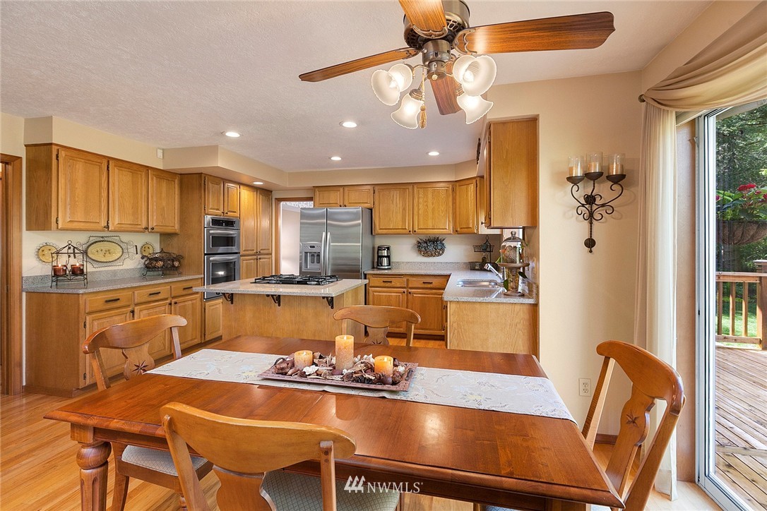 4933 211th Street Southeast Bothell, WA 98021 - Photo 5 of 25 a kitchen with a dining table chairs and refrigerator