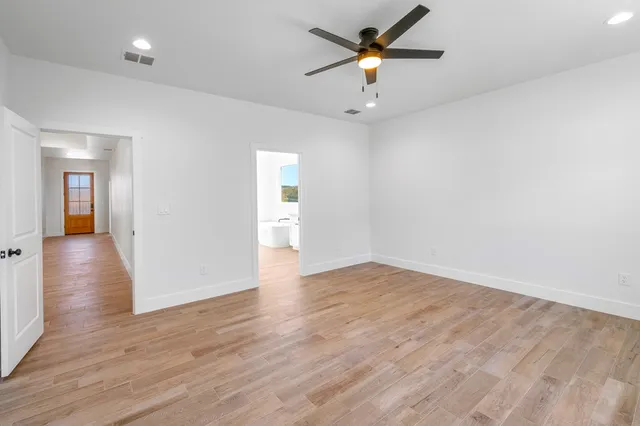an empty room with wooden floor and a ceiling fan
