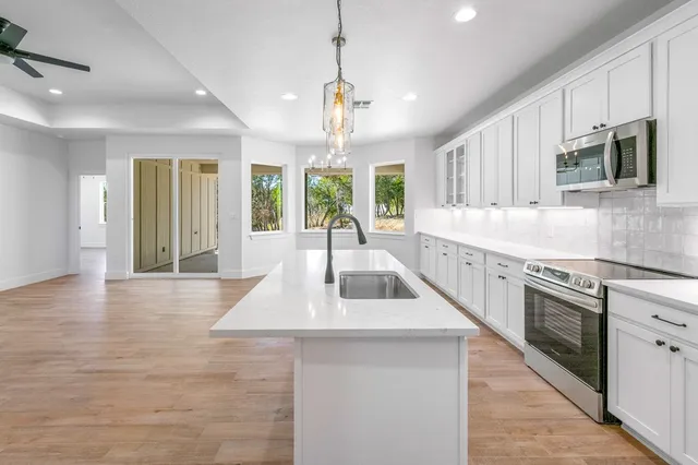 a large kitchen with stainless steel appliances granite countertop a sink a stove a oven a dining table and chairs with wooden floor