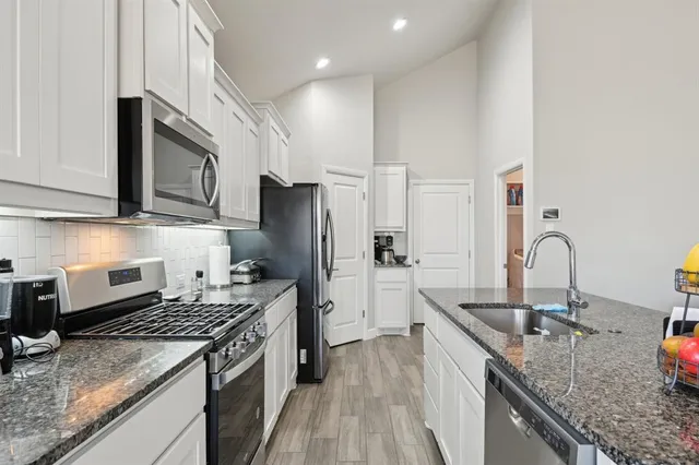 a kitchen with stainless steel appliances granite countertop a sink stove and refrigerator