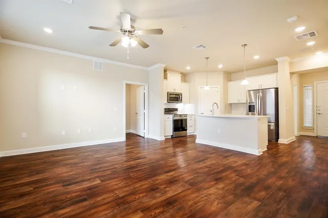 a view of an empty room with a kitchen and wooden floor