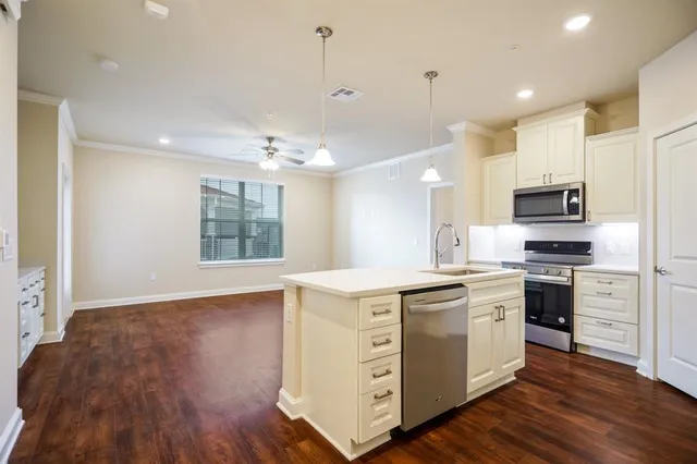 a kitchen with stainless steel appliances a refrigerator a stove a sink and white cabinets