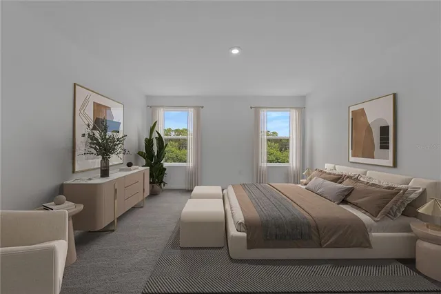 a bedroom with a large bed couch and windows