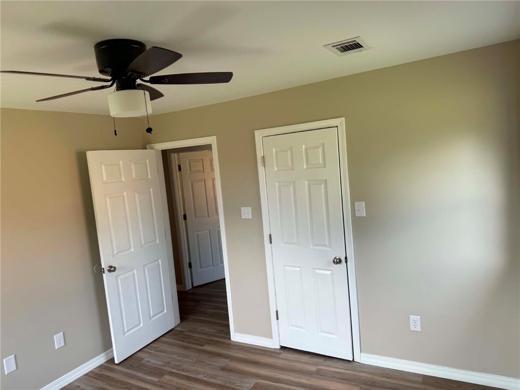 2106 Military Road Dardanelle, AR 72834 - Photo 9 of 16 Wood-finish flooring, neutral wall tones, white trim, five-panel interior doors, and a ceiling fan with integrated lighting