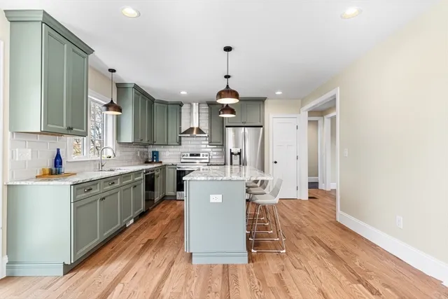 a kitchen with stainless steel appliances granite countertop a refrigerator a stove top oven a sink dishwasher and white cabinets with wooden floor