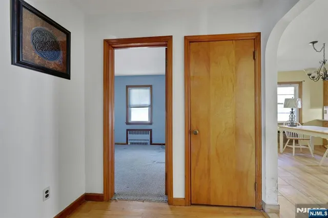 a view of a hallway with wooden floor and a bathroom