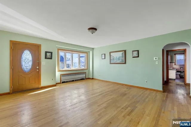 a view of an empty room with window and wooden floor