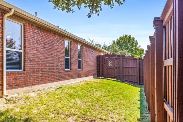 a view of a backyard with wooden fence and a large tree