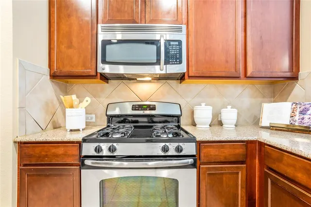 a kitchen with granite countertop a stove top oven microwave and cabinets