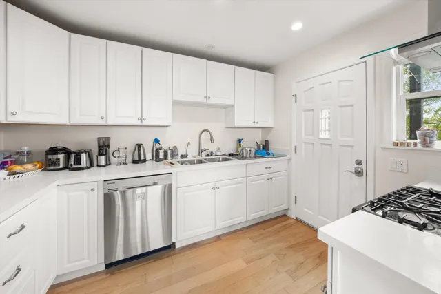 a kitchen with stainless steel appliances granite countertop a refrigerator sink and white cabinets