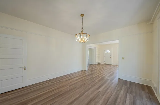 a view of a room with wooden floor and chandelier