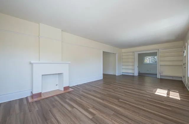 a view of empty room with wooden floor and fireplace
