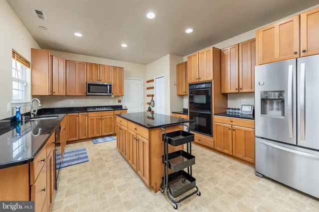 a kitchen with kitchen island granite countertop a stove top oven microwave and refrigerator