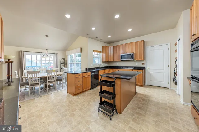 a kitchen with kitchen island granite countertop wooden cabinets and a refrigerator