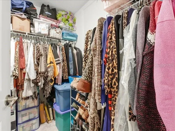 a view of walk in closet with clothes and shoes